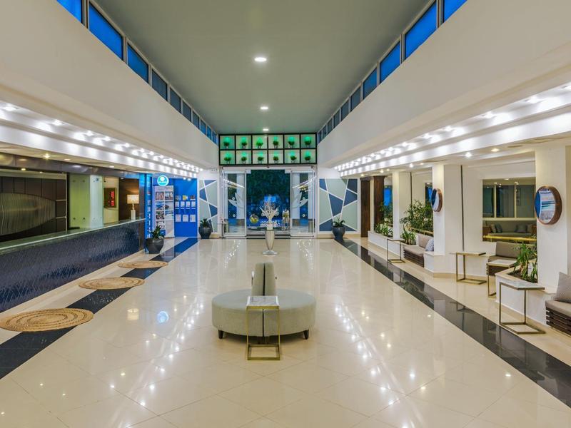 Světlá hotelová hala s lesklou podlahou, zónami k sezení a moderním designem.