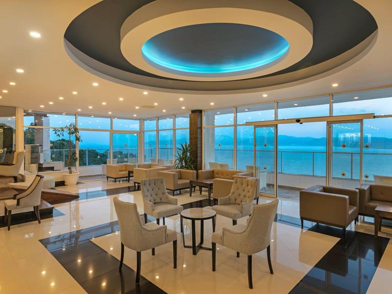 Moderní hotelový salonek s panoramatickými okny s výhledem na pláž a moře.