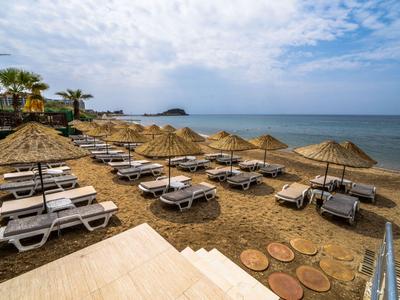 Spiaggia con lettini e ombrelloni di paglia proprio sul mare sotto un cielo azzurro.