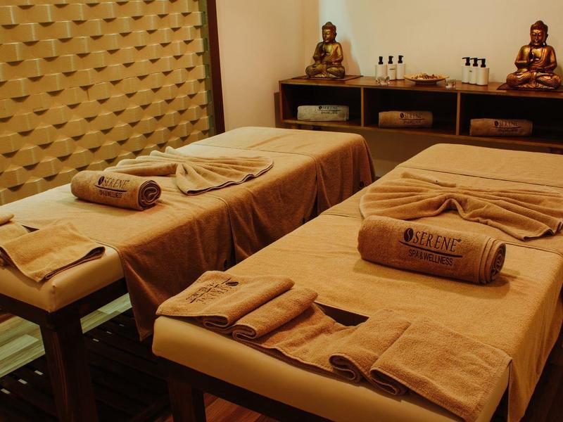 Two massage tables with towels set in a cozy spa room featuring warm lighting and wooden decor.