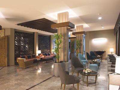 Hall d'hôtel moderne avec groupes de sièges, plantes et ambiance chaleureuse.