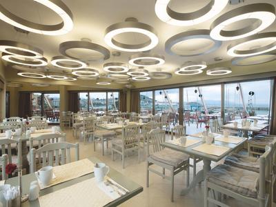 Restaurant lumineux avec des lumières rondes modernes au plafond et vue sur la promenade en bord de mer.