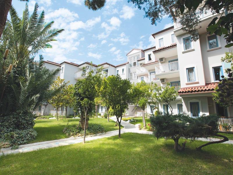 Bâtiment d'hôtel entouré d'arbres verts et de pelouse sous un ciel bleu