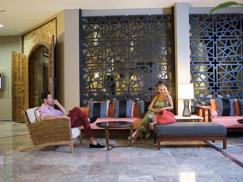 Deux femmes se détendent dans un hall d'hôtel élégant avec une décoration moderne et des panneaux en bois.