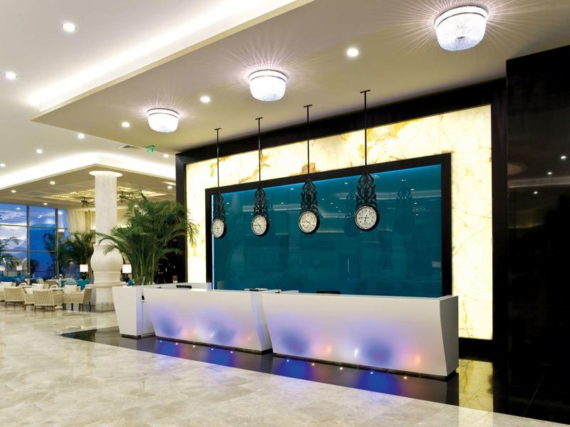 Moderne Empfangstheke mit Pendelleuchten, blauer Rückwand und Marmorboden in hellem Raum.