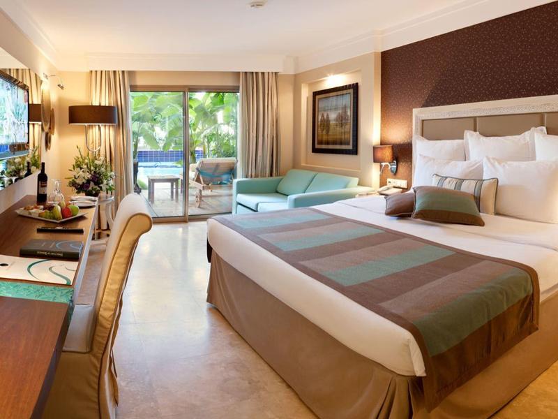 Modernes Hotelzimmer mit zwei Betten, Schreibtisch, Fernseher und Balkon mit Blick ins Grüne.