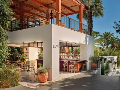 Moderner Außenbereich eines Hotels mit Bar, Sitzgelegenheiten und tropischen Pflanzen.