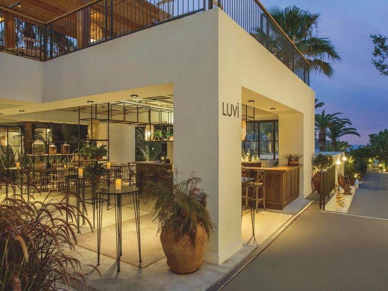 Area ristorante esterna moderna di un hotel con illuminazione calda al tramonto.