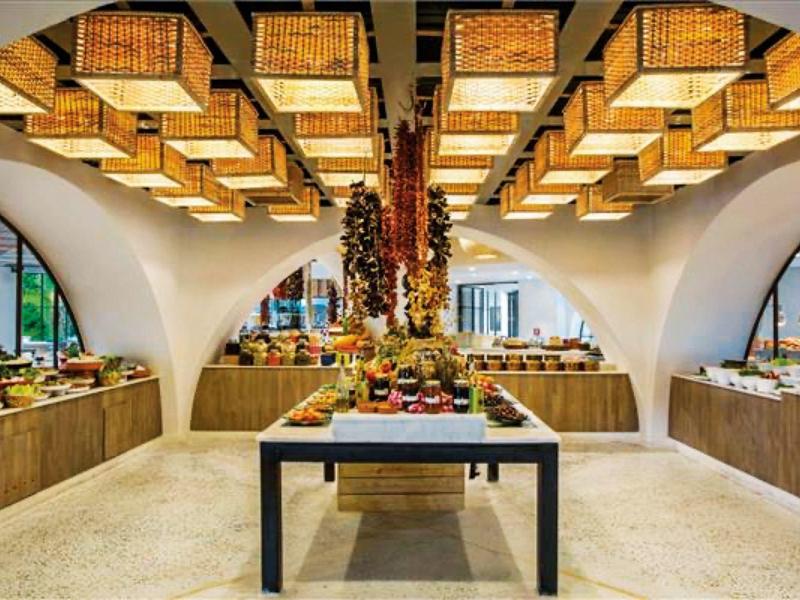 Buffet moderno in hotel con cesti decorativi sul soffitto e varietà di piatti su tavoli di legno.