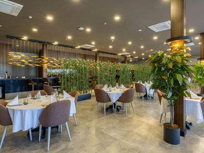 Modernes Restaurant mit stilvoll dekorierten Tischen und grünen Pflanzen.