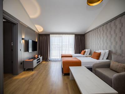 Modern eingerichtetes Hotelzimmer mit Sofa, zwei Betten und großen Fenstern.