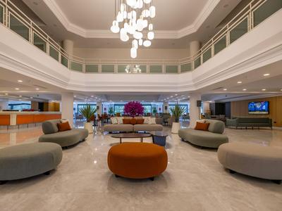 Große Hotellobby mit modernen Sofas und Kronleuchter, heller Marmorboden und hohe Decke.