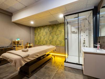 Behandlungsraum mit Massagebett, moderner Dusche und entspannender Beleuchtung im Hotel-Spa.