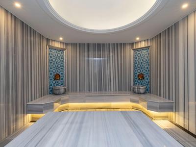 Moderner Spa-Raum mit Marmorliege und gedämpfter Beleuchtung zur Entspannung.