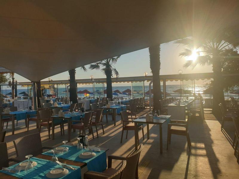Terrazza del ristorante con posti a sedere, vista mare al tramonto.