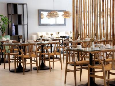 Restaurante moderno con muebles de madera y decoración natural en una sala luminosa.