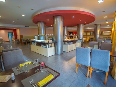 Moderner Frühstücksbereich mit blauen Stühlen und Buffetstation in einem Hotel.