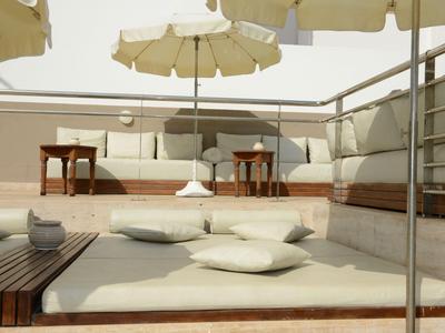 Moderner Außenbereich mit gepolsterten Sitzbänken, Kissen und Sonnenschirmen auf einer Terrasse.