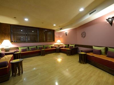 Gemütlicher Hotel-Lounge-Bereich mit Holzmöbeln, Polstern und indirekter Beleuchtung.