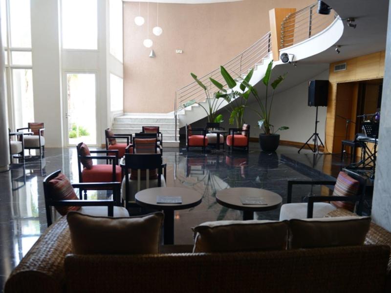 Großer Raum mit hohen Fenstern, vielen Sitzgelegenheiten und moderner, heller Einrichtung.