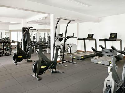 Modernes Fitnessstudio mit Cardio-Geräten und Gewichten in hellem Raum