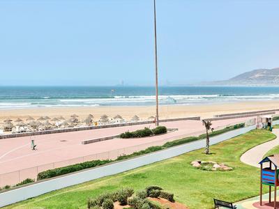 Spiaggia con ombrelloni, passeggiata, aree verdi e parco giochi vicino al mare.