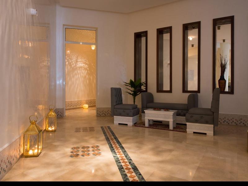 Corridor elegante dell'hotel con area salotto, lanterne dorate e specchi decorativi a parete.