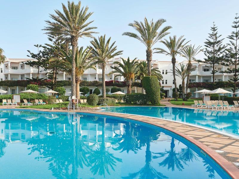 Grande piscina con palme e edifici bianchi sullo sfondo sotto un cielo limpido