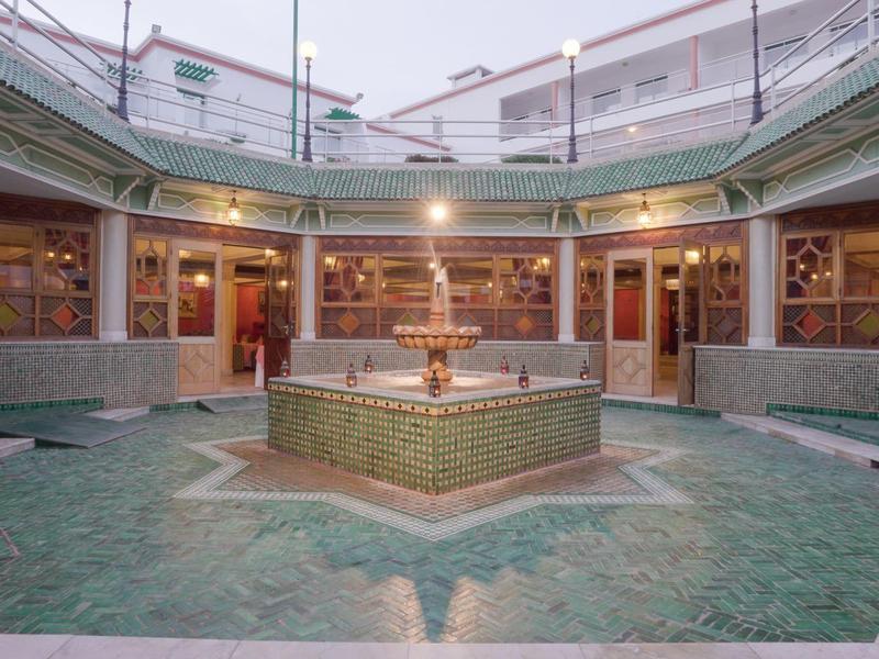 Une cour intérieure avec une fontaine centrale et une architecture de style méditerranéen dans un hôtel.
