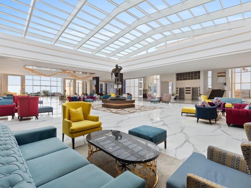 Großer heller Raum mit Glasdach, bequemen bunten Sesseln und Tischen in modernem Lounge-Design.