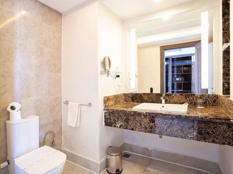 Helles Badezimmer mit weißer Toilette, Marmorwaschbecken und großem Spiegel.