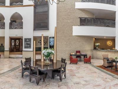 Amplio vestíbulo de hotel con elegantes áreas de descanso y arquitectura luminosa y abierta.