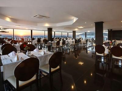 Elegantes Restaurant mit gedeckten Tischen und Panoramablick auf den Sonnenuntergang.
