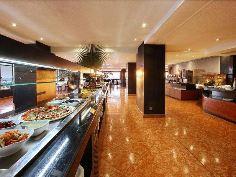 Velká hotelová jídelna s bufetem nabízejícím různé teplé a studené pokrmy.