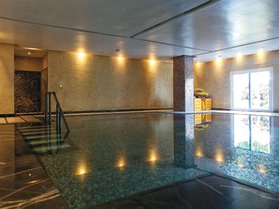 Innenbereich mit einem ruhigen, reflektierenden Hallenbad und sanfter Beleuchtung.