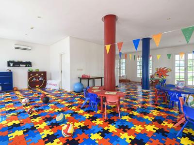 Heller Spielraum mit buntem Puzzle-Boden und Kindertischen im Hotel.