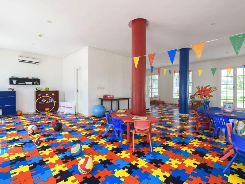 Heller Spielraum mit buntem Puzzle-Boden und Kindertischen im Hotel.