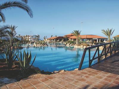 Piscine d'hôtel avec palmiers et terrasse sous un ciel clair