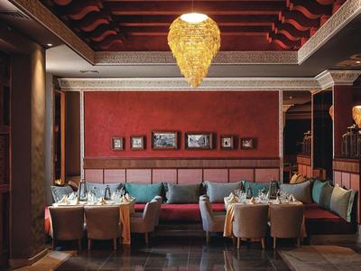 Restaurant élégant avec un mur rouge, des sièges confortables et un grand lustre.