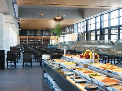 Restaurant moderne avec buffet et nombreuses places assises près de grandes fenêtres.