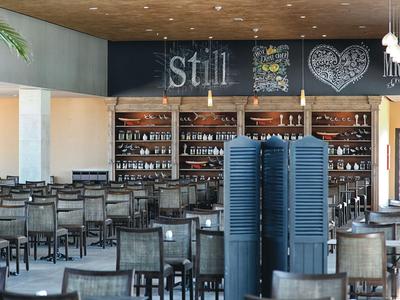 Restaurant moderne avec de nombreuses chaises, étagères en bois et tableau noir au mur.
