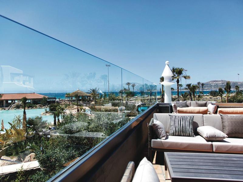 Vue panoramique depuis une terrasse d'hôtel avec des sièges et vue sur la mer.