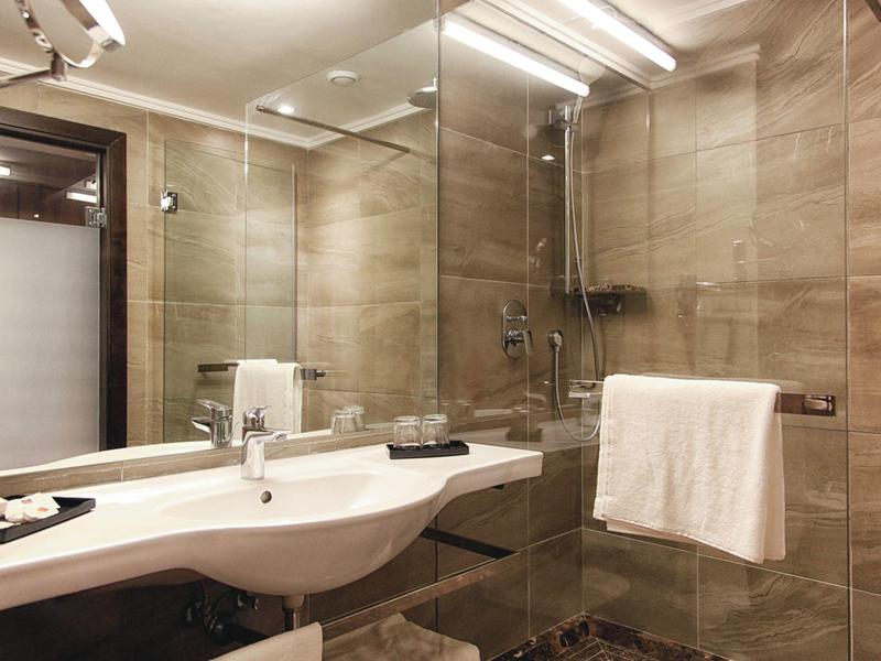 Salle de bain moderne avec grande douche en verre et miroir éclairé.