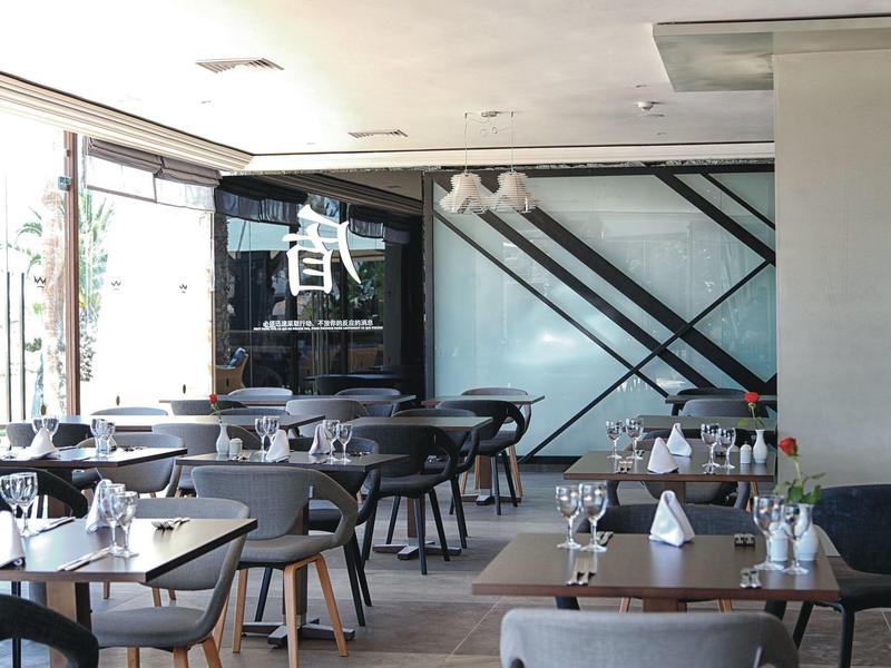 Salle de restaurant d'hôtel moderne avec tables et chaises dans une ambiance lumineuse.