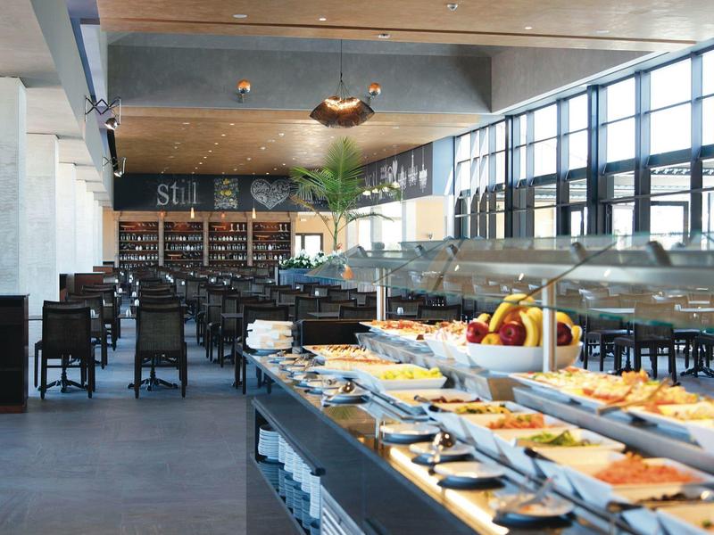 Restaurant moderne avec un buffet spacieux et de grandes fenêtres laissant entrer beaucoup de lumière naturelle.