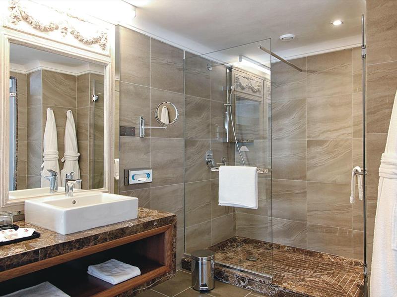 Salle de bain moderne avec douche en verre, lavabo sur comptoir en bois et serviettes.