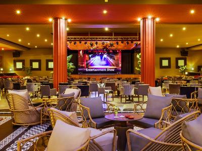 Gemütlicher Veranstaltungsraum mit Bühne, Sofas und stilvollen Sitzgelegenheiten in warmem Licht.