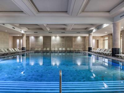 Overdekt hotelzwembad met blauw verlicht water en ligstoelen