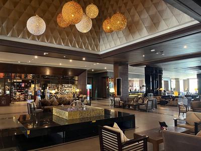 Großzügige Hotellobby mit bequemen Sitzgelegenheiten und dekorativen hängenden Lampen.