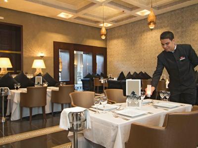 Elegant restaurant met gedekte tafels en ober die serveert.